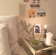 a small table with flowers, candles and pictures on the wall above it in a bedroom