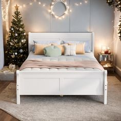 a white bed sitting in a bedroom next to a christmas tree with lights on it