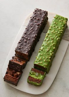 three different types of chocolate and green desserts on a white plate, one is cut in half