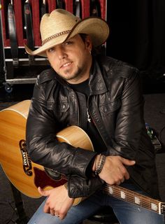 a man with a cowboy hat sitting in front of a guitar