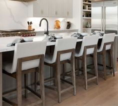 a kitchen with white counter tops and chairs