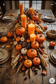 a wooden table topped with lots of pumpkins and candles