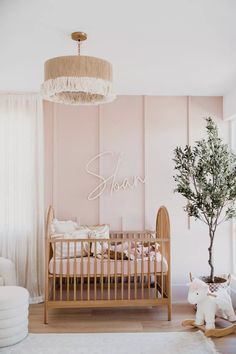 a baby's room with a crib, rocking chair and tree in the corner