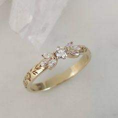 a yellow gold ring with three diamonds on it's side, sitting on a white surface