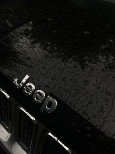 the front end of a black and white truck with rain drops on it's hood