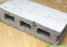 a cement block sitting on top of a wooden table next to a brick with holes in it