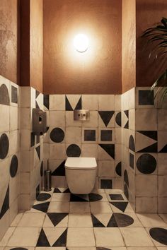 a white toilet sitting inside of a bathroom next to a plant