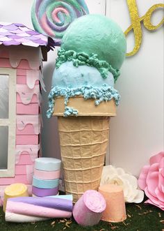 an ice cream cone with blue and green frosting in front of a pink house