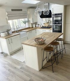 a large kitchen with an island counter and stools in the center, along with two hanging lights