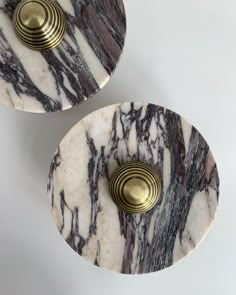 two white and black marble plates with brass handles on each side, sitting next to each other