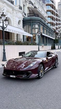 a red sports car parked on the street in front of some tall buildings with balconies