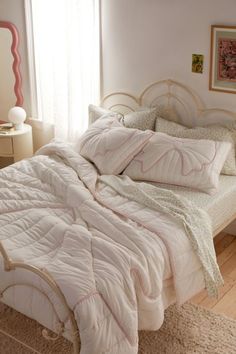 a bed with white comforter and pillows on top of it in a bedroom next to a window