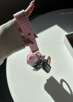 a hand holding a cell phone keychain attached to a chain with a heart on it