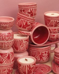 red and white pottery is stacked on top of each other in front of a pink wall