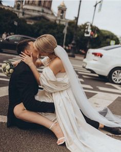 a bride and groom sitting on the ground in front of a crosswalk with their arms around each other