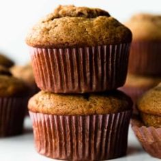 three muffins stacked on top of each other next to a jar of apple cider