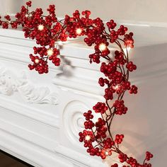 red berries are on the mantle with lights