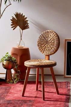 a wicker chair sitting on top of a red rug next to a potted plant