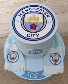 a cake that is sitting on top of a wooden table with the name manchester city on it