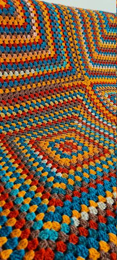 a multicolored crocheted blanket is laying on the floor