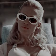 a woman wearing sunglasses sitting in a chair