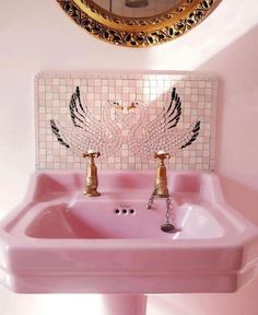 a pink sink with gold faucet and mirror above it