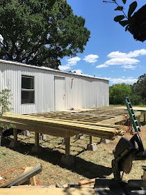 a house being built in the middle of a field with a sawhorse next to it