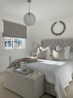 a bedroom with a bed, ottoman and chandelier