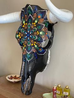 a cow's skull decorated with multicolored beads sits on a wooden table