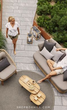 a woman walking down a sidewalk next to two couches and a coffee table