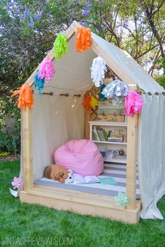 a dog bed in the shape of a tent with flowers on it and a stuffed animal inside