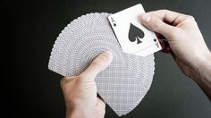 a hand holding playing cards in front of a black background