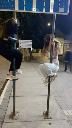 two women are hanging upside down on street signs