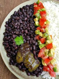 a plate with rice, beans and vegetables on it sitting on a wooden table top