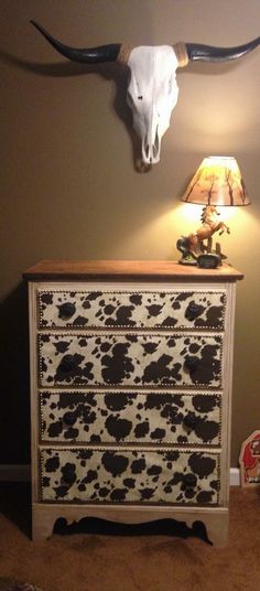 a cow skull mounted on the wall next to a leopard print dresser in a bedroom