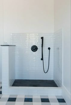 a bathroom with black and white checkered flooring, shower head and hand shower