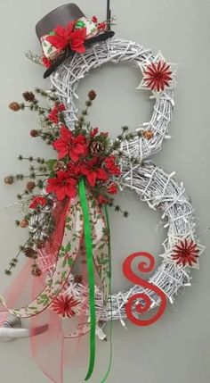 a white wreath with red flowers and a black top hat on it, hanging from the wall