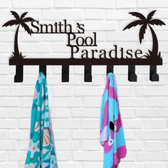 two towels are hanging on a rack in front of a white brick wall with the words smith's pool paradise