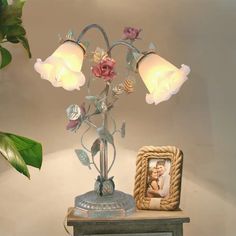 a lamp that is sitting on top of a table next to a photo frame and potted plant