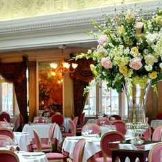 a dining room with tables and chairs covered in white tablecloths, pink linens and flowers