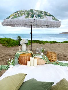 an umbrella is set up on the beach with candles and other items to decorate it