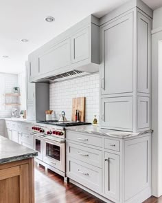 a large kitchen with white cabinets and wood flooring, along with marble counter tops