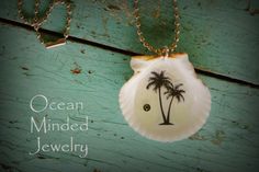 a white shell with a palm tree on it and the words ocean minded jewelry written below