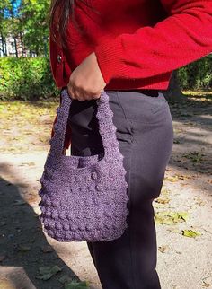 a woman is holding a purple purse in her hands