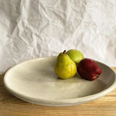 two pears and one apple on a white plate