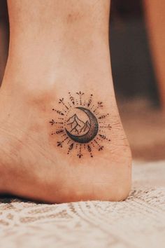 a small tattoo on the foot of a person with mountains and stars in the background