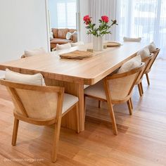 a dining room table with chairs and a vase filled with flowers on top of it