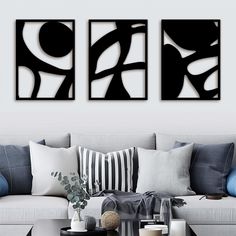 two black and white abstract paintings on the wall above a couch in a living room