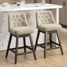 two beige barstools sitting in front of a white counter top with marble backsplash