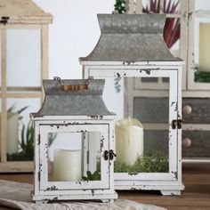 two white lanterns sitting on top of a table next to each other with candles in them